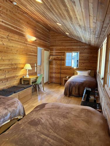 a log cabin bedroom with two beds and a desk at 貸し別荘 Key of Private Villa 'ムササビハウス' in Kita-karuizawa