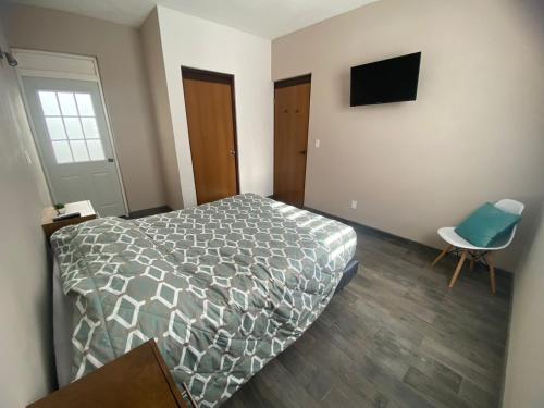 a bedroom with a bed and a chair and a television at Departamento ‘El Chulo’ en Palapa Ochoa in Loreto