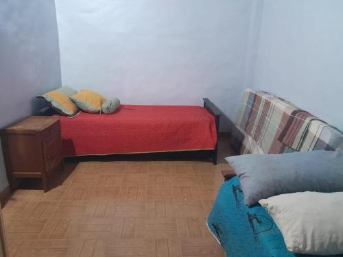 1 dormitorio con cama roja y sofá en No Reservar en San Vicente