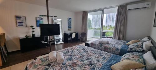 a bedroom with two beds and a flat screen tv at Hermoso estudio con vista al mar en el Town Center de Playa Blanca Panamá in Río Hato