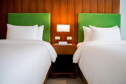 Timberland Highlands Resort في San Mateo: سريرين في غرفة الفندق مع طاولة مع مصباح