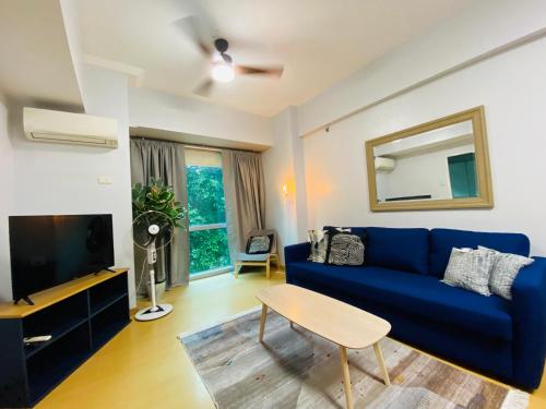 een woonkamer met een blauwe bank en een tv bij Avant at the Fort by Urban Realty in Manilla