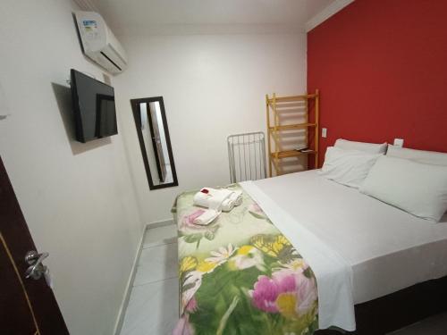 um quarto com uma cama e uma parede vermelha em Pousada Canto dos Corais em Maragogi