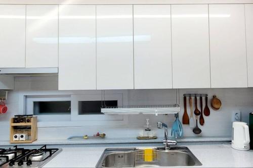 a kitchen with white cabinets and a sink at Stay Mono in Incheon