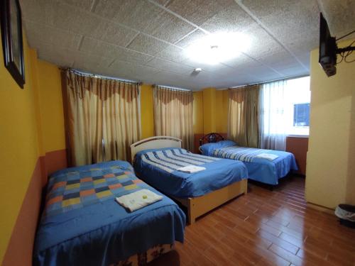 2 camas en una habitación con paredes amarillas en HOTEL CARIBEAN REAL en Latacunga