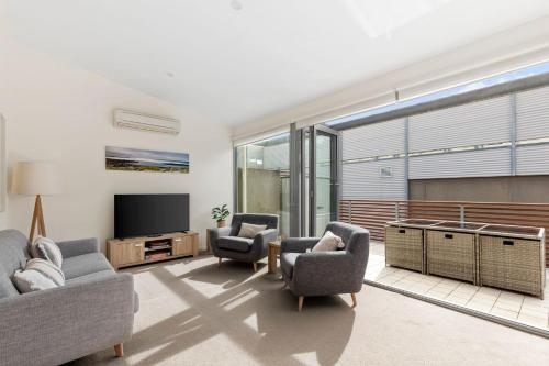 a living room with two chairs and a television at Beach House at Lonnie in Point Lonsdale