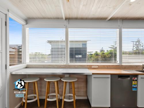 a kitchen with three bar stools in front of a window at Stones Throw to Beach & Chiton Surf Club in Hayborough