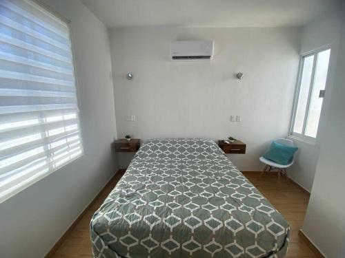 ein Schlafzimmer mit einem Bett in einem Zimmer mit zwei Fenstern in der Unterkunft Departamento ‘El Bello’ en Palapa Ochoa in Loreto
