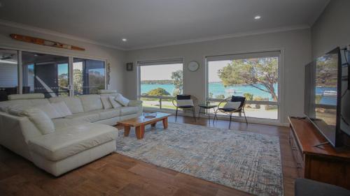 een woonkamer met een witte bank en een televisie bij Waterfront on Osprey in Coffin Bay