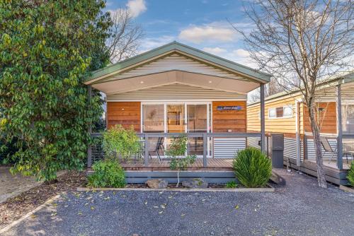 una casa con un porche con un árbol en BIG4 Tasman Holiday Parks - Bright en Bright