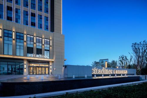 an office building with a sign in front of it at Citadines Jinqiao Building Yantai in Yantai