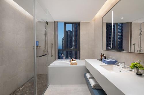 een badkamer met een douche, een bad en een wastafel bij Citadines Jinqiao Building Yantai in Yantai