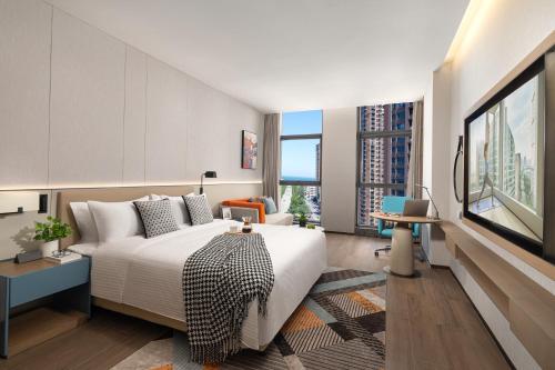 um quarto com uma cama grande e uma janela grande em Citadines Jinqiao Building Yantai em Yantai