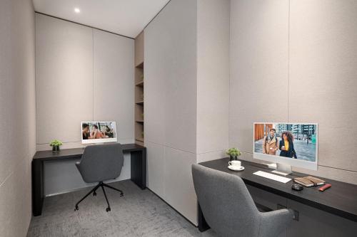 a desk with a computer and a chair in a room at Citadines Jinqiao Building Yantai in Yantai