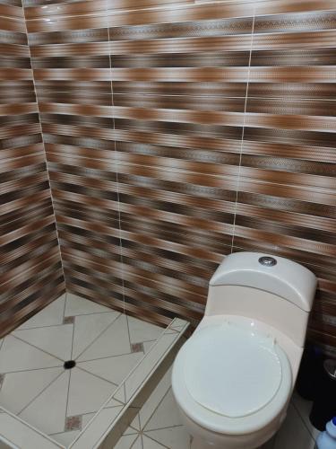 a bathroom with a toilet and a tiled wall at DEPA CENTRICO CARAZ in Caraz