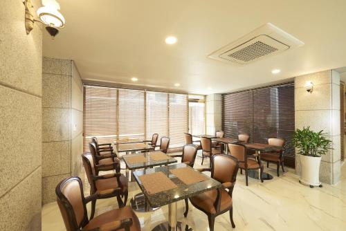 a restaurant with tables and chairs and windows at Noble Hotel in Seoul