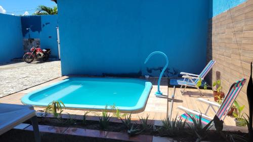 una piscina con 2 sillas y una pared azul en República Francês, en Marechal Deodoro