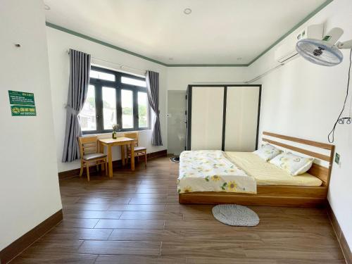 Schlafzimmer mit einem Bett, einem Tisch und einem Schreibtisch in der Unterkunft Leo's Homestay Phan Rang in Phan Rang
