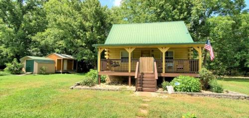 a tiny house with a green roof and a deck at Yellow Cabin on the River cabin in Newport