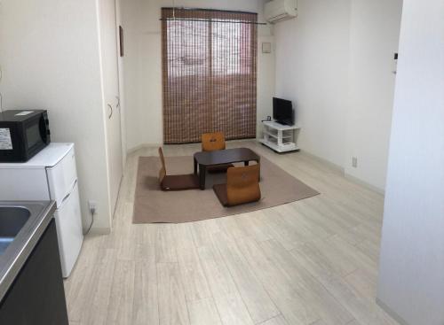 a living room with a table and chairs and a television at Apartment Heights HANA in Sakai