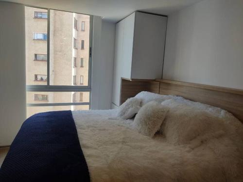 sypialnia z dużym białym łóżkiem i oknem w obiekcie Loft 2019 La Candelaria estrenar 24/7 w mieście Bogota
