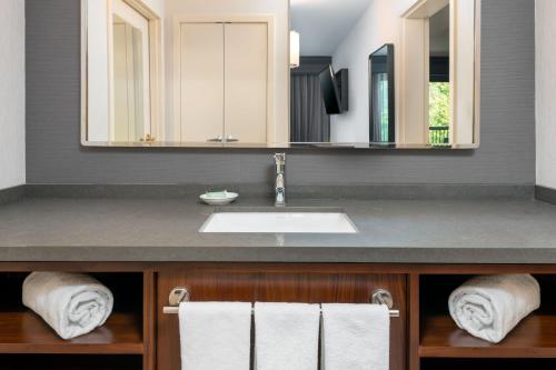 a bathroom with a sink and mirrors and towels at Courtyard by Marriott Danbury in Danbury