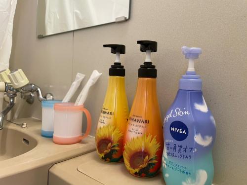 3 botellas de productos de limpieza sentadas en el lavabo del baño en Tokyo Stay Dolce, en Tokio