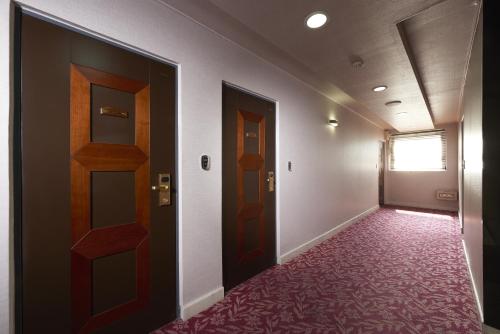 an empty hallway with two doors and a red carpet at Noble Hotel in Seoul