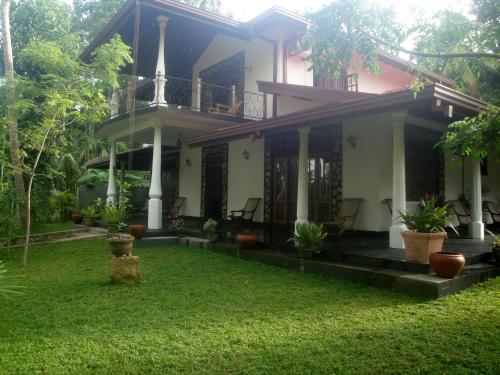 a house with a green yard in front of it at Priyanka Villa in Bentota