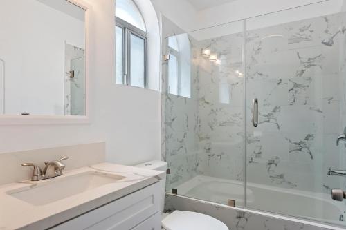 a white bathroom with a shower and a sink at Modern loft close to Universal studio and Hollywood for 8 in Los Angeles