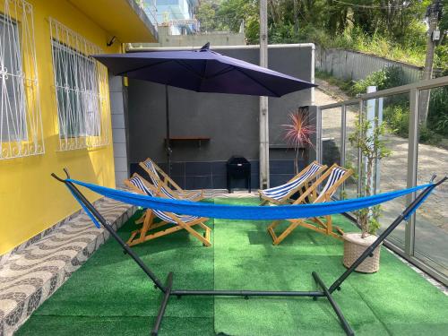 uma rede de descanso, 2 cadeiras e um guarda-sol numa varanda em República Descolada em Florianópolis