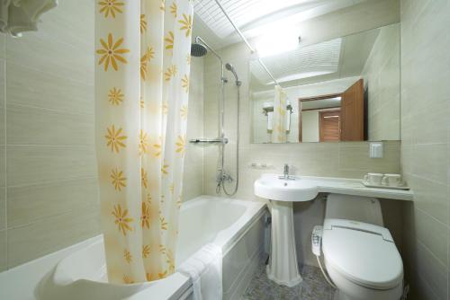 a bathroom with a toilet and a tub and a sink at Noble Hotel in Seoul