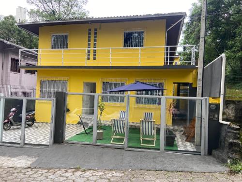 une maison jaune avec deux chaises et un parasol dans l'établissement República Descolada, à Florianópolis