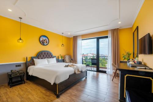 1 dormitorio con paredes amarillas y 1 cama con escritorio en Athenia Boutique Hotel & Spa, en Hoi An
