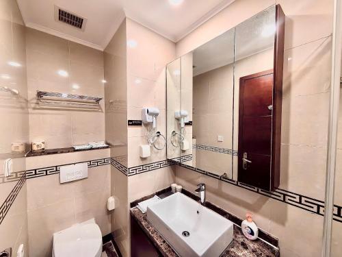 a bathroom with a sink and a mirror and a toilet at Qingdao Elegant Central Apartment in Qingdao