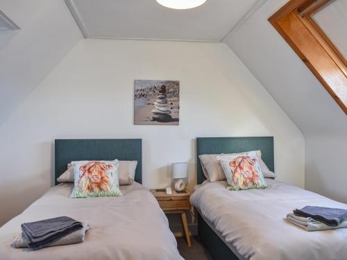 2 Betten in einem Zimmer mit weißen Wänden in der Unterkunft Strathlene Lodge 
