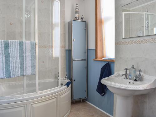 uma casa de banho com um lavatório, um chuveiro e uma banheira e um lavatório. em Strathlene Lodge 