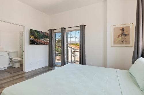 a white bedroom with a bed and a balcony at Modern loft close to Universal studio and Hollywood for 8 in Los Angeles