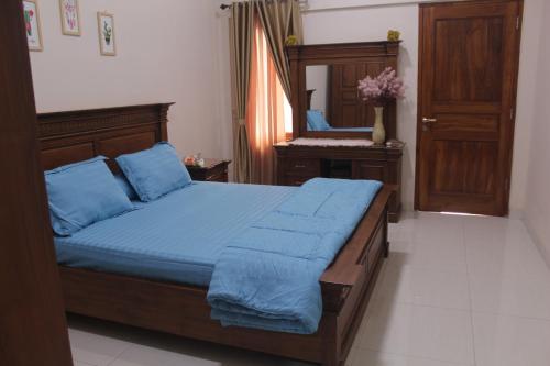 um quarto com uma cama com lençóis azuis e um espelho em Homestay Bougenville Antapani Syariah em Bandung