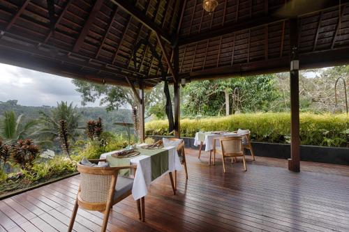 a dining room with tables and chairs on a wooden deck at Black Penny Villas Ubud in Ubud