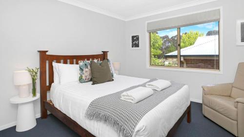 Un dormitorio con una cama y una silla y una ventana. en Highlands on Alice, en Bowral