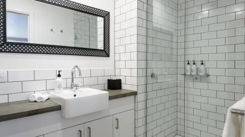 a white bathroom with a sink and a mirror at Daylesford Art Motel in Daylesford