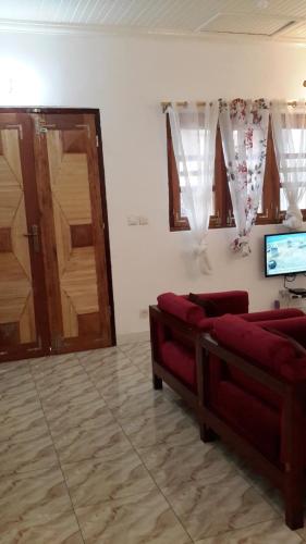 a living room with two red couches and a tv at Résidence Agnès et Victor (RAV) in Bangui