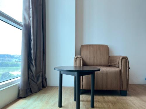 een stoel en een tafel in een kamer met een raam bij Cube Plus Signature Hotel OUG Kuala Lumpur in Kuala Lumpur