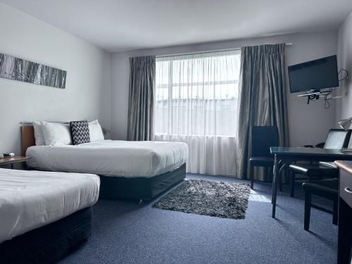 a hotel room with two beds and a desk at Best Western Wellington in Johnsonville