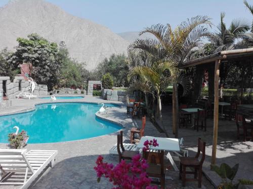 a swimming pool with a table and chairs and a mountain at II IMPERIO in Cieneguilla