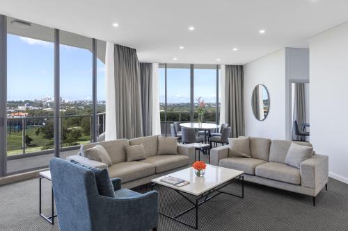 a living room with couches and chairs and a table at Meriton Suites Waterloo in Sydney