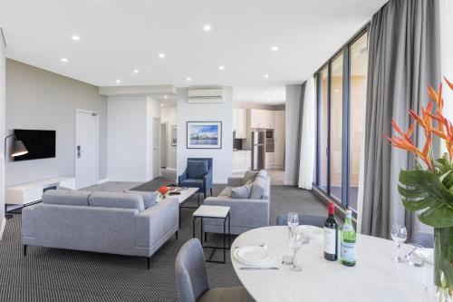 a living room with couches and tables at Meriton Suites Waterloo in Sydney