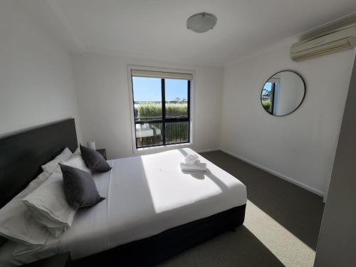 a white bedroom with a large bed and a window at Oceanic on Thompson Apartments in Cowes