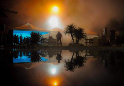 un hombre de pie junto a una piscina por la noche en Rancho los Emilios en Alausí